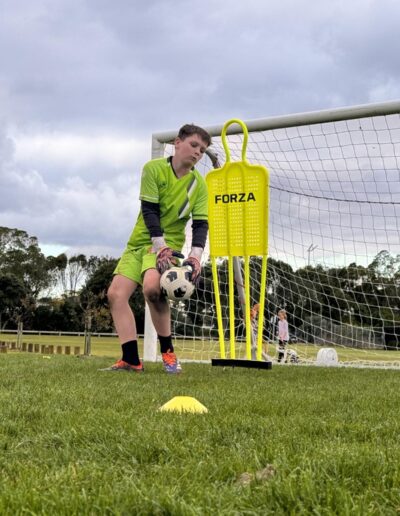 Young football goalie practicing saves with PureFootball coach